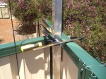 Two rusty G-clamps attaching a support to two pieces of intersecting fence